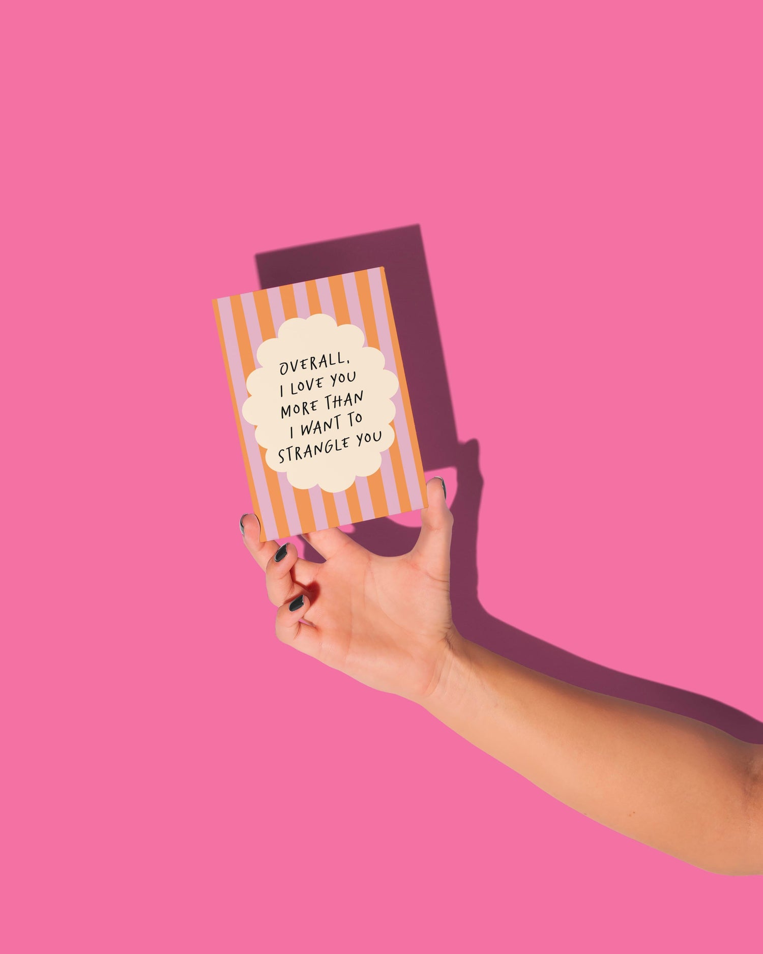 Hand holding a striped card with text on a pink background