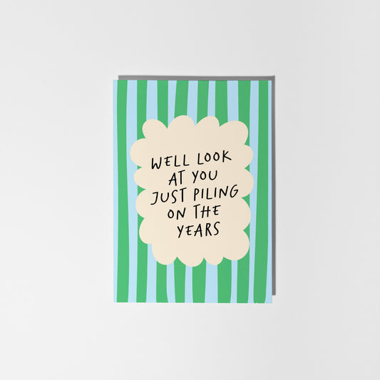 Greeting card with text 'Well look at you just piling on the years' on a striped background