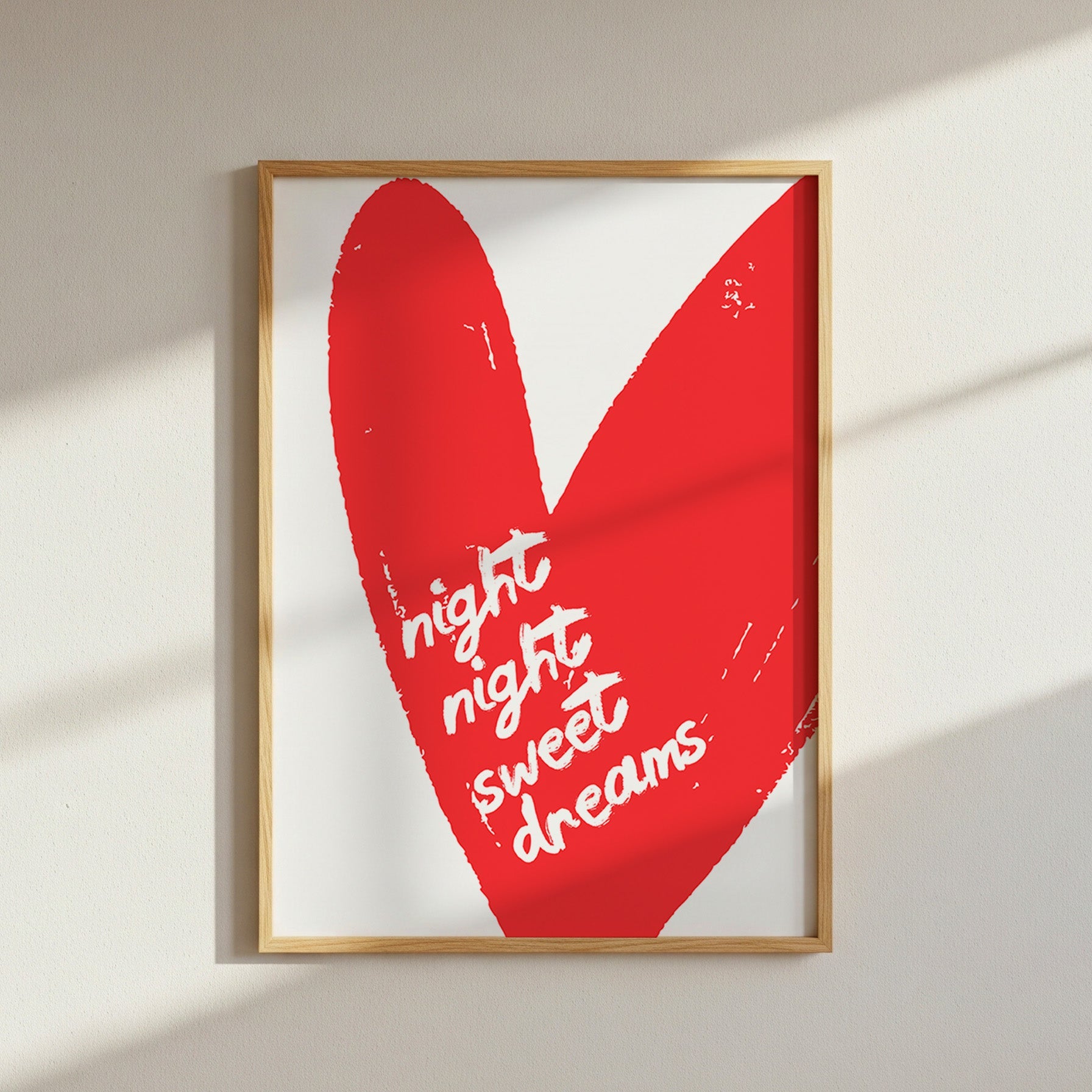 Framed artwork with a red heart and 'night night sweet dreams' text on a white wall.